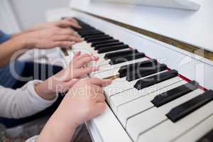 Mid section of mother and daughter playing piano