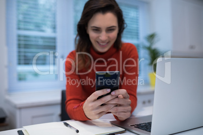 Woman using mobile phone at desk