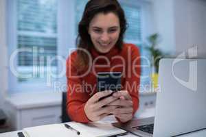 Woman using mobile phone at desk