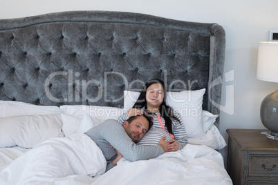 Man and pregnant woman relaxing in bedroom