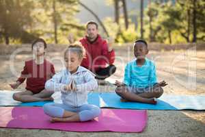 Coach and kids meditating in park