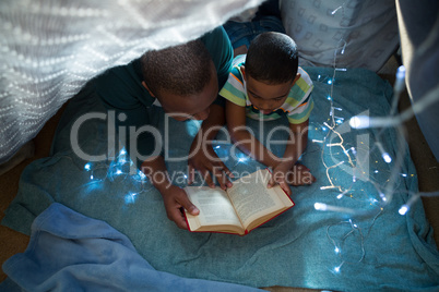 Father and son reading book in bedroom