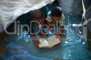 Father and son reading book in bedroom