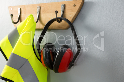 Protective workwear and earmuffs hanging on hook
