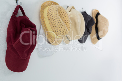 Various straw hats and caps hanging on hook