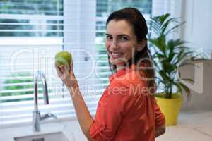 Woman holding a green apple in kitchen