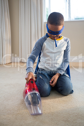 Boy in superhero costume cleaning a floor with vacuum cleaner