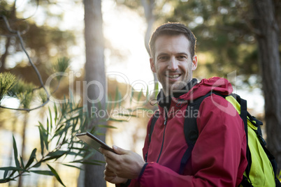 Portrait of happy man holding digital tablet in forest