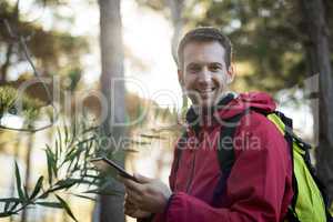 Portrait of happy man holding digital tablet in forest