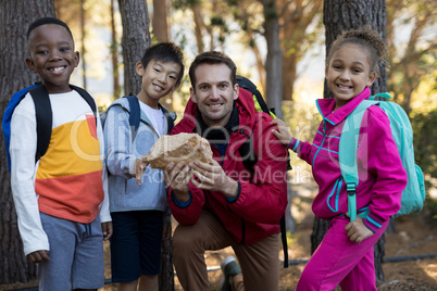 Portrait of teacher and kids examining rock