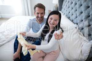 Portrait of happy couple holding baby clothes
