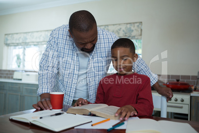 Father helping his son with homework in kitchen