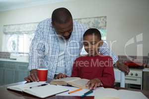 Father helping his son with homework in kitchen