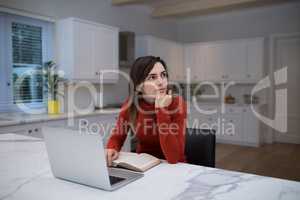 Woman sitting with laptop and book at desk