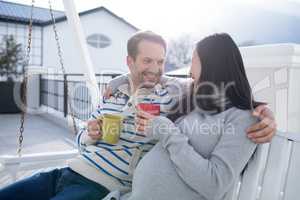Couple having coffee on a porch swing in balcony