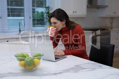 Woman using laptop while having coffee