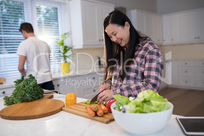 Pregnant woman chopping vegetables in kitchen