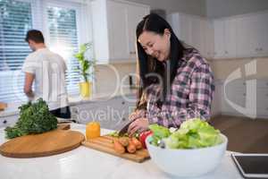 Pregnant woman chopping vegetables in kitchen