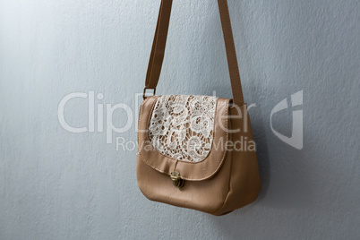 Stylish handbag hanging against wall