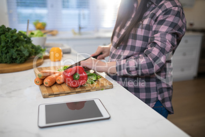 Pregnant woman chopping vegetables in kitchen