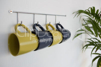 Close-up of colorful mugs hanging on hook