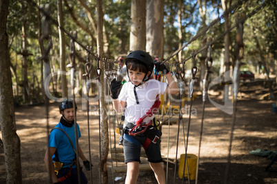 Cute boy crossing zip line in parkland