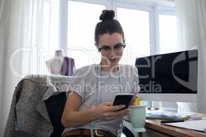 Female designer using mobile phone while having coffee