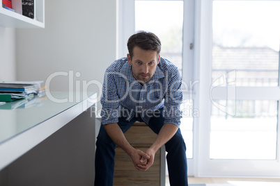Portrait of confident man sitting on drawer