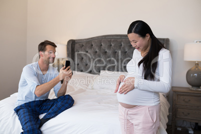 Man taking picture of woman with mobile phone