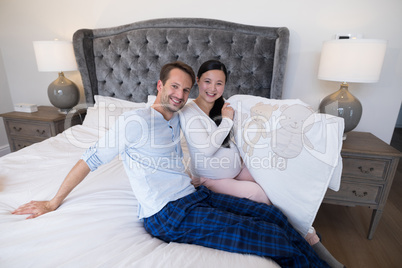 Portrait of happy couple holding picture of teddy bear