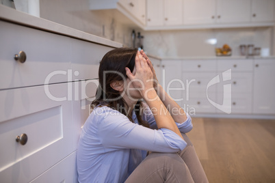 Worried woman sitting in kitchen