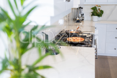 Pizza on baking tray in kitchen