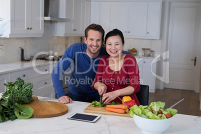 Couple chopping vegetables to prepare salad in the kitchen