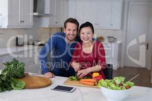 Couple chopping vegetables to prepare salad in the kitchen