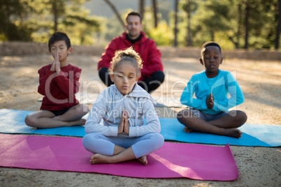 Coach and kids meditating in park