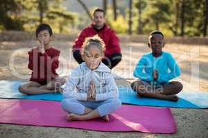 Coach and kids meditating in park
