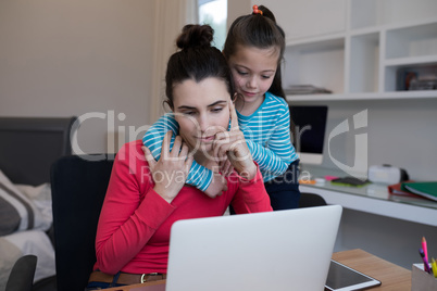 Mother and daughter using laptop at desk