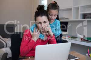 Mother and daughter using laptop at desk