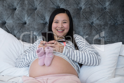 Woman using mobile with pair of socks on her stomach