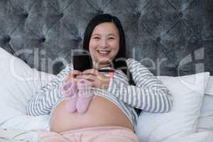 Woman using mobile with pair of socks on her stomach