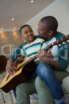 Father teaching his son to play the guitar