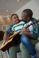 Father teaching his son to play the guitar