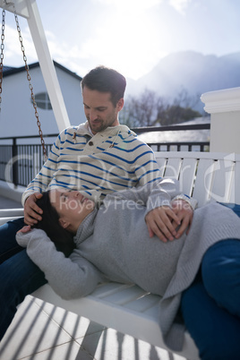 Couple relaxing together on a porch swing in balcony