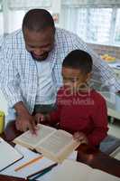Father helping his son with homework in kitchen