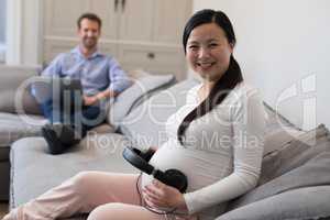 Pregnant woman placing headphones on her stomach