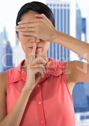 Businesswoman covering eyes with hand in city and hushing quiet with finger