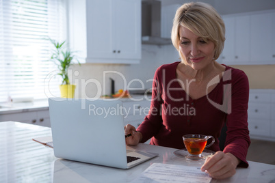 Woman looking at bill in kitchen