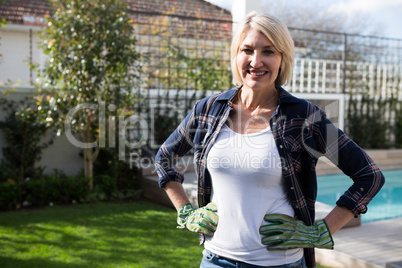 Portrait of happy woman standing with hands on hip