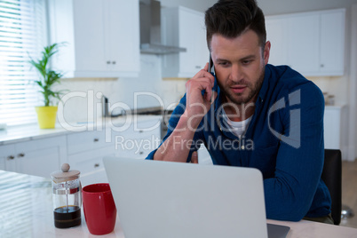 Handsome man talking on mobile phone in kitchen