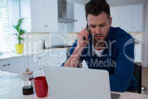 Handsome man talking on mobile phone in kitchen